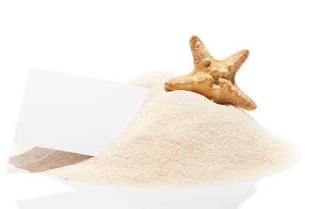 Blank white visit card with starfish on pile of beach sand, isolated on white backgroundの写真素材