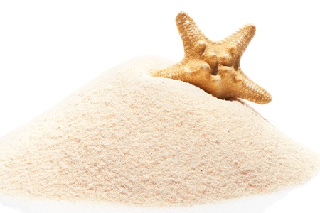 Starfish on pile of beach sand isolated on white backgroundの写真素材