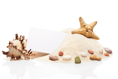 Blank white visit card, starfish, sea shell and stones on pile of beach sand, isolated on white backgroundの写真素材