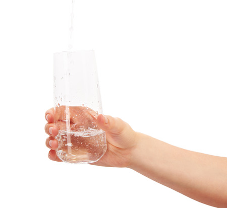 Water pouring into full drinking glass in woman's hand isolated on  white background.の写真素材