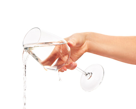 Water pouring from full wine glass in woman's hand isolated on  white background.の写真素材
