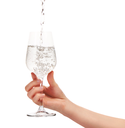 Water pouring into full wine glass in woman's hand isolated on  white background.の写真素材