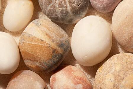 Close up of sea stones on sand. Summer beach background. View from aboveの写真素材
