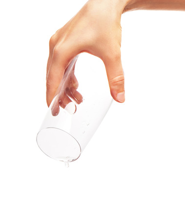 Drop of water falling from empty drinking glass in woman's hand isolated on  white background.の写真素材
