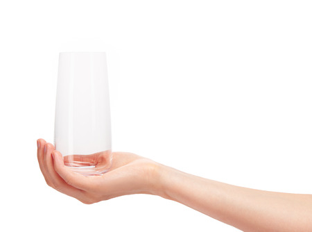 Close up of female hand holding empty clean transparent drinking glass against white background.の写真素材