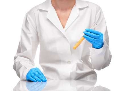 Close up of female in white gown and blue gloves holding transparent white glass  test tube with yellow sorbent against white backgroundの写真素材