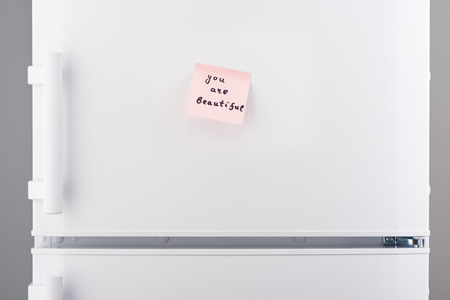 You are beautiful note on light pink sticky paper on white refrigerator doorの写真素材
