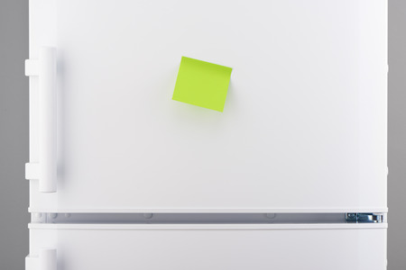 Blank green sticky paper note on white refrigerator doorの写真素材