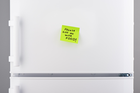 Please feel me with food note on green sticky paper on white refrigerator doorの写真素材