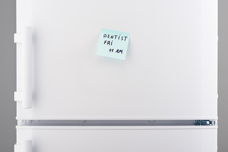 Dentist on friday 11 am note on light blue sticky paper on white refrigerator doorの写真素材