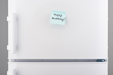 Happy Birthday note on light blue sticky papers on white refrigerator doorの写真素材