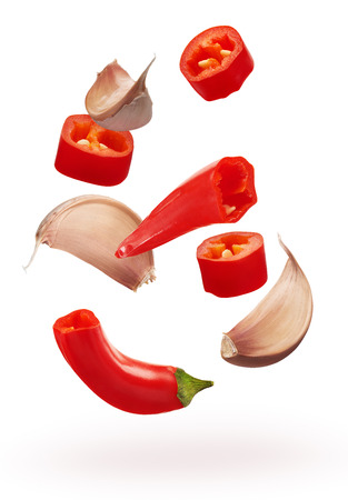 Cut red chili pepper vegetables and cloves of garlic isolated on white backgroundの写真素材