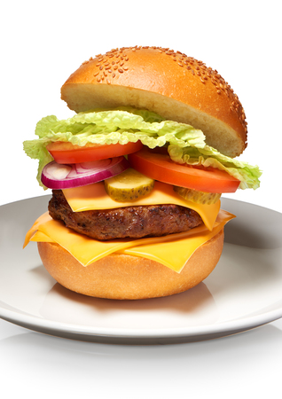 Clouse up of delicious hamburger with cheese, pickles, tomato, onions and lettuce on white plate isolated on white background. Clipping path includedの写真素材