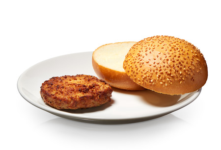 Single grilled hamburger and fresh bun with sesame seeds on white plate isolated on white background. Clipping path included の写真素材