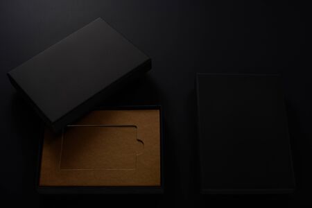 Slick black gift boxes with brown cardboard inside on black background