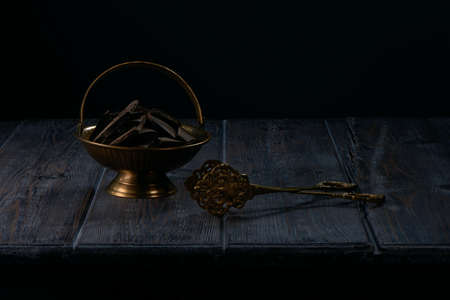 Dark chocolate in antique copper bowl on old wooden table background
