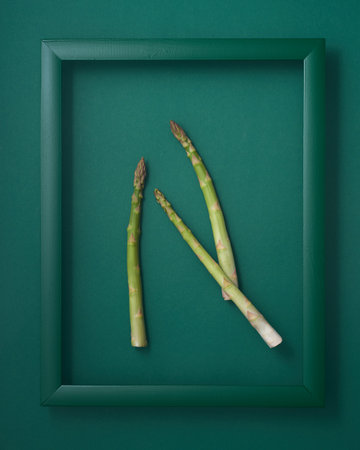 Asparagus in wooden picture frame on green backgroundの写真素材