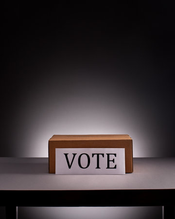 Voting box on desk with free space above it on gray background with dramatic lightingの写真素材