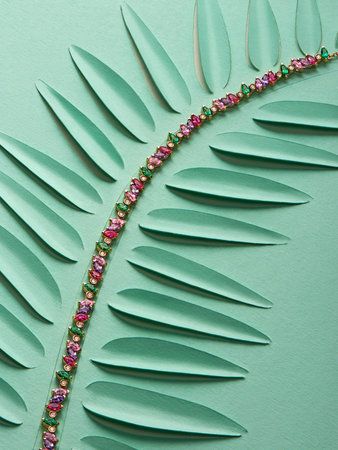 Artistic photography of luxury gold necklace with natural gemstones on green paper leaf. Love and wedding concept.の写真素材