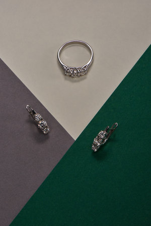 Artistic photography of luxury ring and earrings with natural diamonds on grey, green and white paper. Love and wedding concept.の写真素材