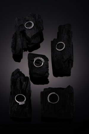 Artistic photography of luxury rings with natural diamonds on black coal with reflection. Love and wedding concept.の写真素材