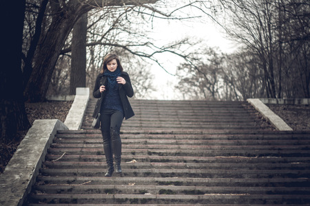 Photo of girl in autumn clothes on a background of urban landscapesの写真素材