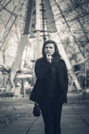 Photo of girl in autumn clothes on a background of urban landscapesの写真素材