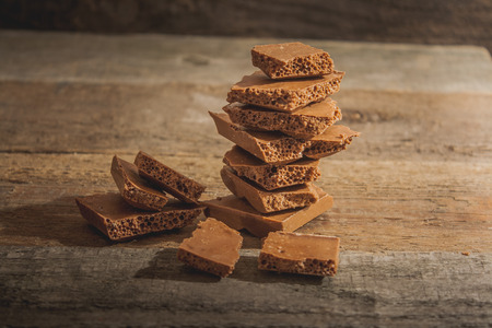 The pieces of porous chocolate on background wooden baseの写真素材