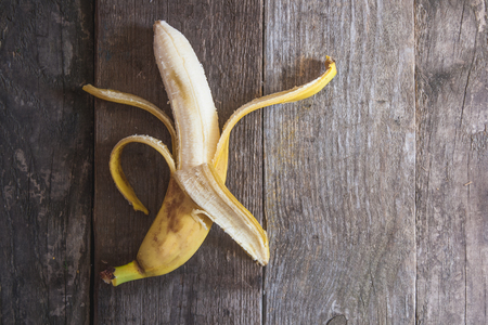 Banana on a background of a wooden framework with treated skinの写真素材