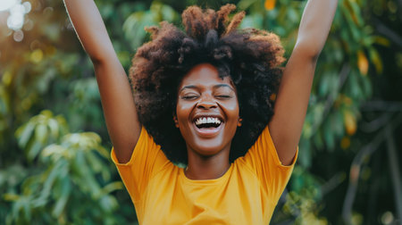 Cheerful african american young woman with afro hairstyle smiling and dancing in the park.の素材