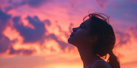 Silhouette of a beautiful Asian woman on the sunset sky backgroundの素材