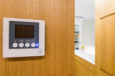 Intercom video door bell on wooden wall in modern apartment