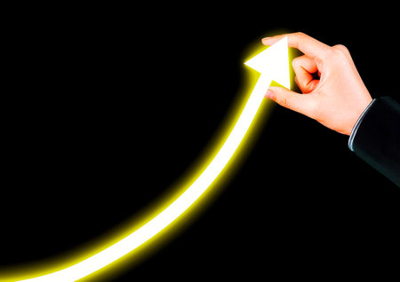 Businessman hand drawing a growing arrow on a black background with copy spaceの写真素材
