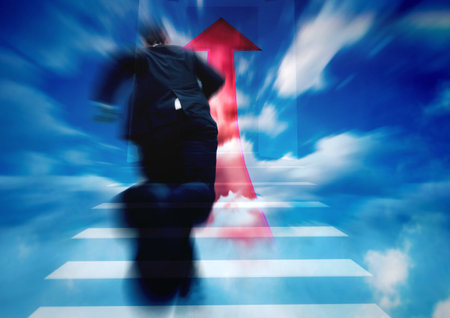 Businessman walking up the stairs with red arrow on blue sky backgroundの写真素材