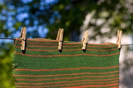 Red and green striped towel pegged to a clothesline with four clothespins. Place for copy textの写真素材