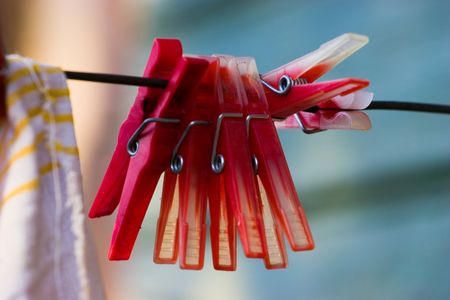 Red plastic clothespins and towel on a black washing line. Selected focus on clothespins with soft...