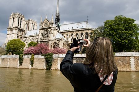 Tourist taking picture of Notre Dame de Paris in spring time. View across the Seine River, Franceの写真素材