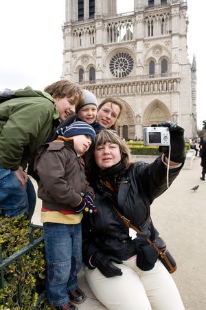 Group of tourists, members of one family taking self portrait at the famous Cathdrale Notre-Dame de Parisの写真素材