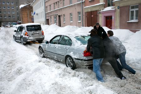 RIGA - FEBRUARY 2: People pushing stuck car in snowy street after heavy snowfall in Riga, Latvia, February 2, 2010 It is extremely cold and snowy winter in Europe (2009-2010).のeditorial素材