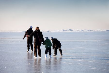 Family ice skating in natural rink frozen seaの写真素材