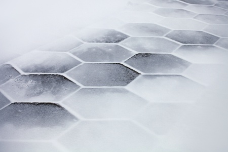 Hexagonal sidewalk tiles covered with snow and iceの写真素材