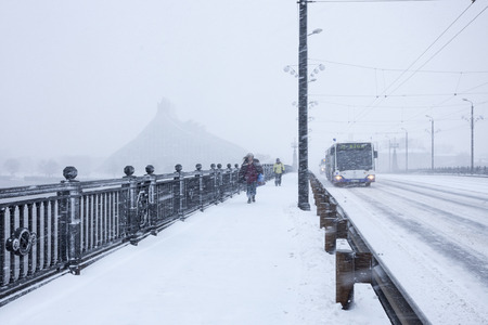 RIGA LATVIA  DECEMBER 25 2014: Unidentified Pedestrians and Bus with text RIGA on Stone bridge during heavy snow storm.のeditorial素材