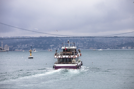 ISTANBUL, TURKEY - MARCH 20, 2011: Small passenger ship  sailing in Bosphorus Strait. Bosphorus suspension bridge seen in background.のeditorial素材
