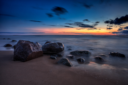 Baltic Sea sunset seascape with wet rocks. Smooth long exposure of wavesの写真素材