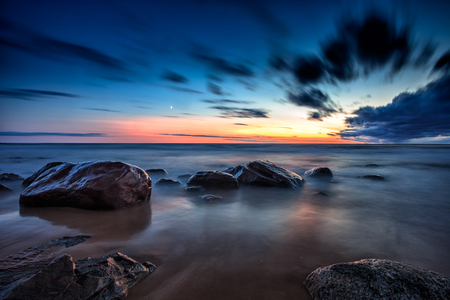 Baltic Sea sunset seascape with wet rocks. Smooth long exposure of wavesの写真素材