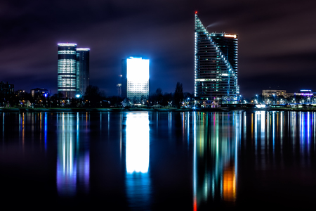 Riga skyline with some skyscrapers. Night shot  with scenic water reflections in Daugava river watersの写真素材