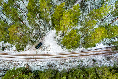 Aerial View Of Black Car On Snow Covered forest roadの写真素材