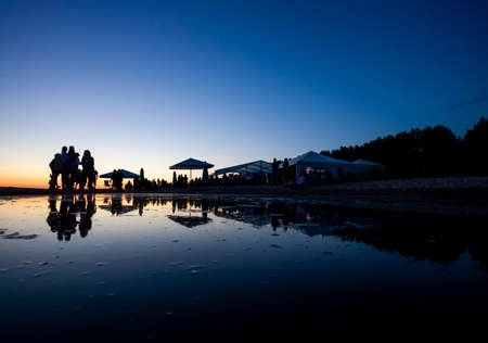 Silhouettes of crowd at seaside bar during sunsetの写真素材