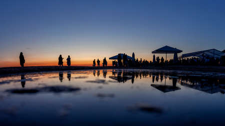 Silhouettes of crowd at seaside bar during sunsetの写真素材