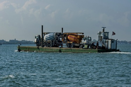 One load flat-boat ferry two concrete mixer truck via the lagoon, Italyの写真素材